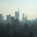 A foggy view of the Milan cityscape with modern skyscrapers and historic architecture.